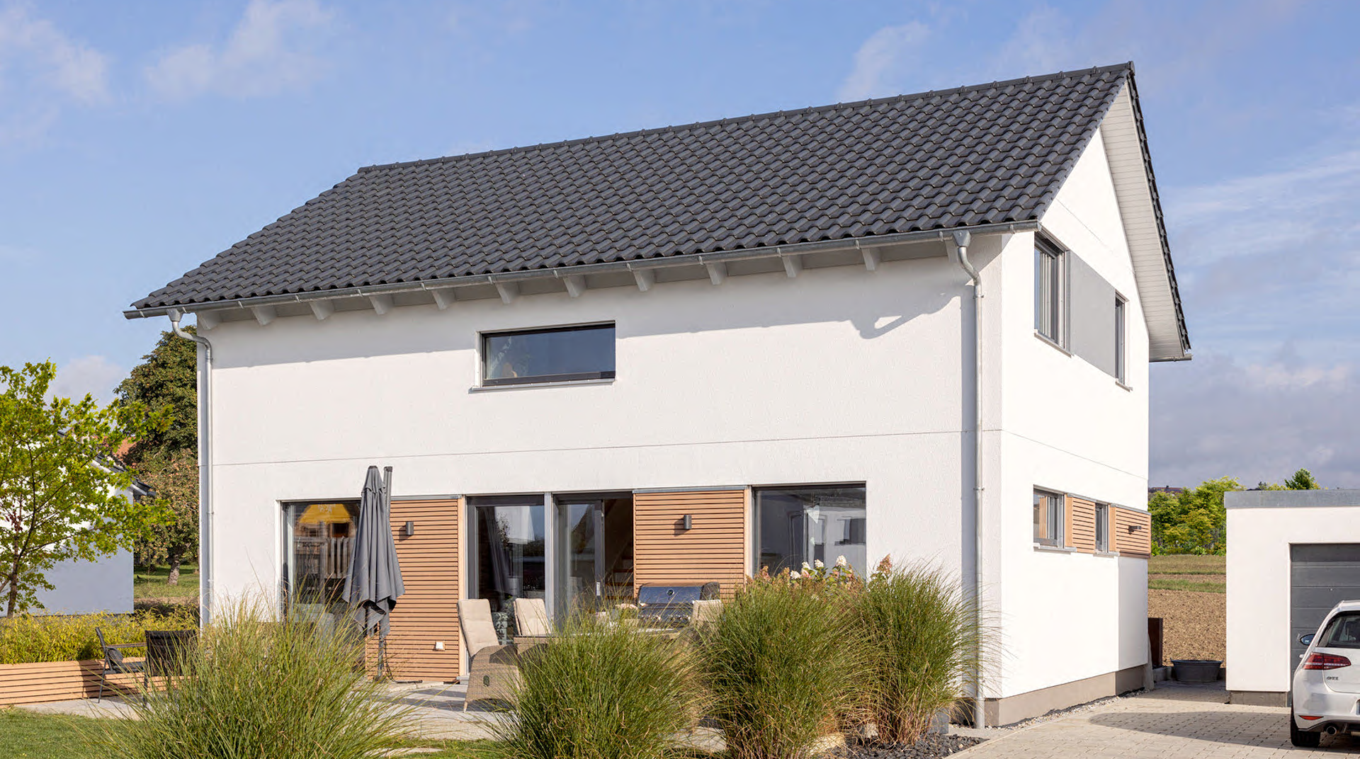 Außenansicht mit Terrasse und Garten, recht sieht man die Garage.