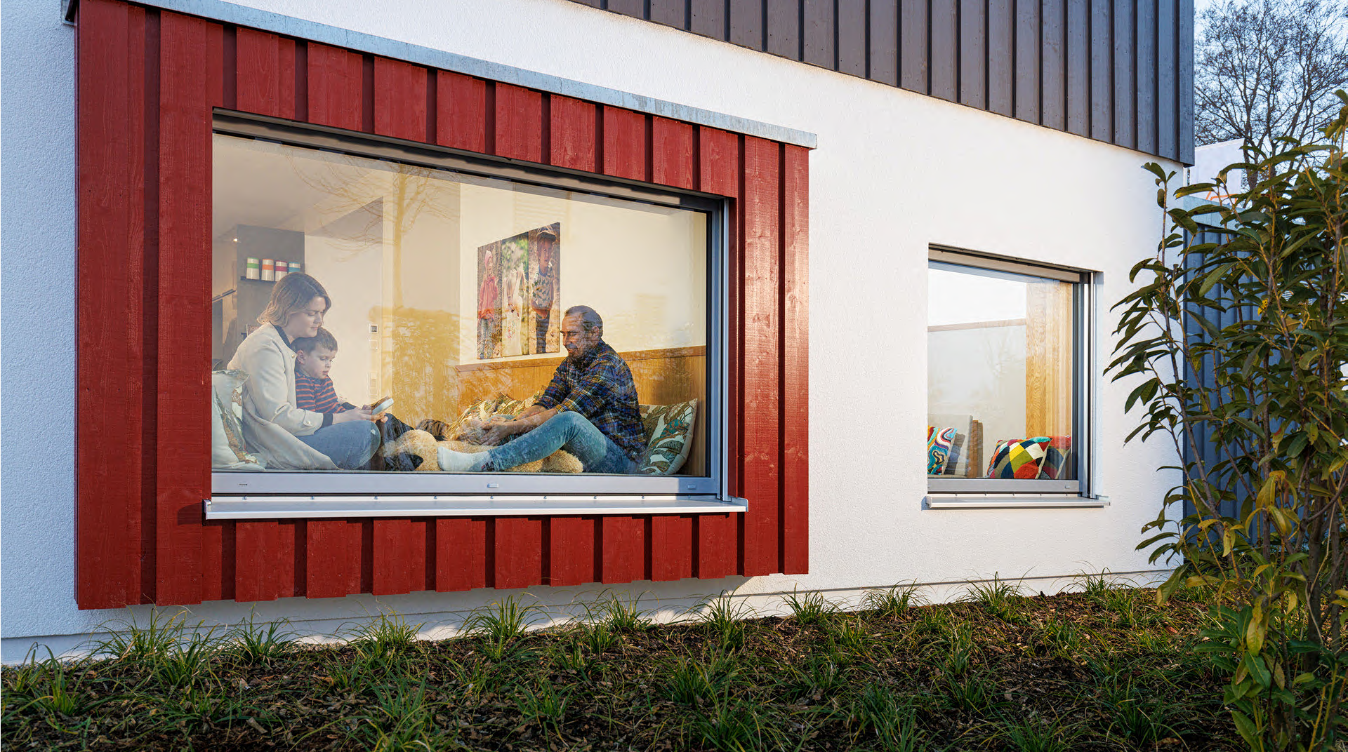 Familie sitzt am großen Wohnzimmerfenster.