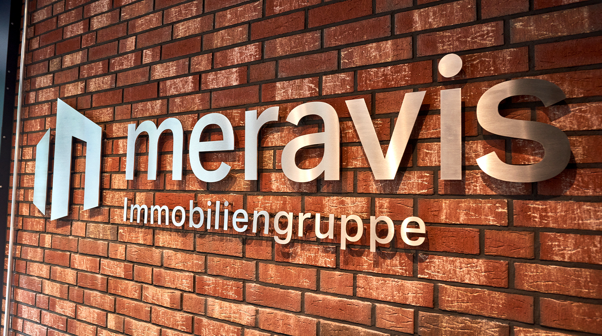 meravis Wohnungsbau- und Immobilien GmbH, Logo auf Backsteinwand