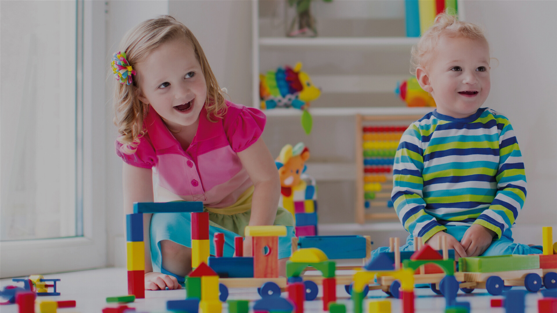 Zwei kleine Kinder spielen im Kinderzimmer mit Bausteinen.